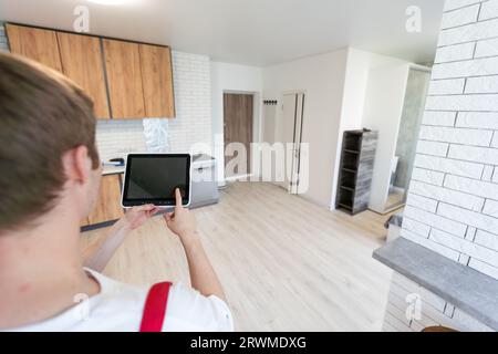Worker with tablet computer checking alarm system indoors. Stock Photo
