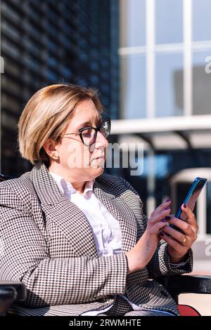 businesswoman using wheelchair typing on mobile Stock Photo