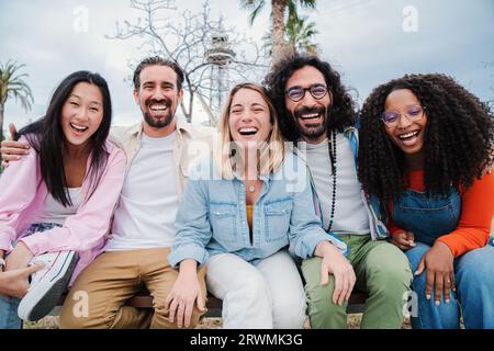 Portrait of a group of happy best friends looking at camera. Young adult people laughing together and staring front. Males and females on a funny meeting at daytime. Friendly mates sitting outside. High quality photo Stock Photo