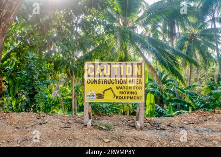 Puerto Galera, Philippines - Apr 22, 2023. A road sign warning of moving equipment in a construction area, with tropical vegetation in the background. Stock Photo