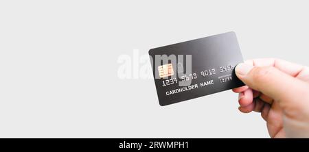 Hand holding luxury credit card on grey background, hand showing black credit card for online shopping and payment, panoramic banner with copy space. Stock Photo