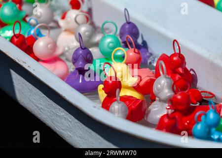 Colorful plastic ducks in the water basin of a traveling carnival stall. Stock Photo