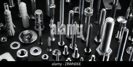 various metal screws, bolts and fasteners on black background Stock Photo