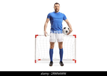 Full length portrait of a soccer player with a ball under arm posing in front of a mini goal isolated on white background Stock Photo