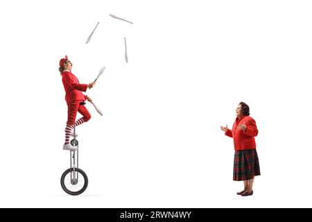 Elderly woman watching an acrobat riding a giraffe unicycle and juggling isolated on white background Stock Photo