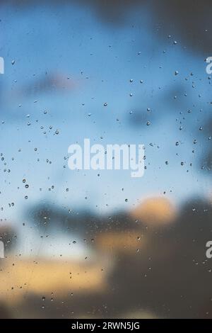 Rain drops and blue sky on window with storm clouds Stock Photo