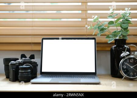 White laptop with blank screen placed on table near window. Stock Photo