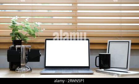 White laptop with blank screen placed on table near window. Stock Photo