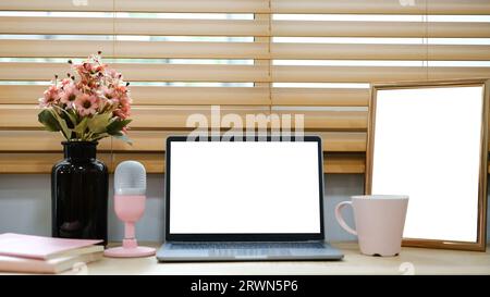 White laptop with blank screen placed on table near window. Stock Photo