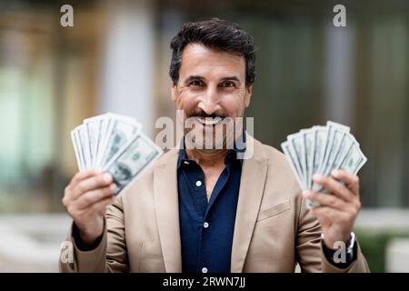 Cash money dollar banknotes in happy middle eastern businessman hand Stock Photo