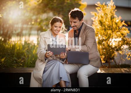 Business people mature man and woman using gadgets at park Stock Photo