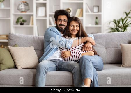 Portrait of beautiful indian couple posing on couch at home Stock Photo