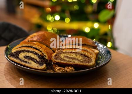 traditional hungarian christmas cookie calles bejgli filled with walnut and poppy seed with christmas tree background . Stock Photo