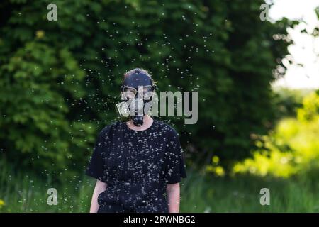girl in a gas mask protects herself from allergies from flying dandelion seeds in a spring park Stock Photo