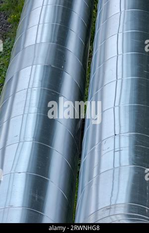 Close-up of two large silver district heating pipelines shining in the sunlight. Stock Photo