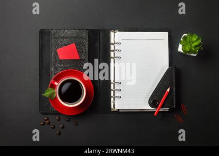 Black office desktop with notebook, credit card and red cup of coffee. Top view. Stock Photo