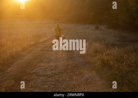 runner running across the field with his dog Stock Photo