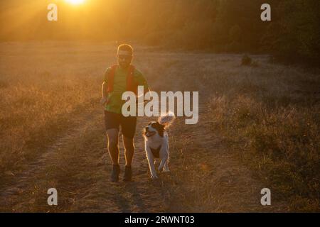 runner running across the field with his dog Stock Photo