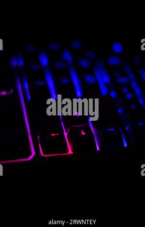 Backlit keyboard of a personal computer, with out-of-focus keys, on a dark background of a desk at night Stock Photo