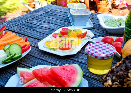 Wooden breakfast table in the garden with various nutrition. Stock Photo