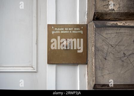 Quirky doorbell sign - Please Do Not Ring Unless Answer Is Required - on a brass by the door of a New Town property in Edinburgh, Scotland, UK. Stock Photo