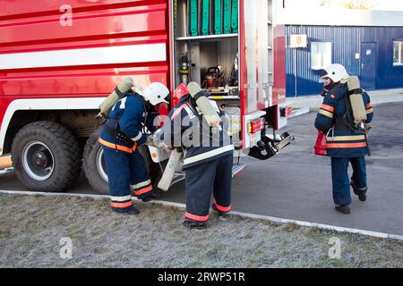 Group of firemen putting on gas masks and preparing for extinguish fire. Stock Photo