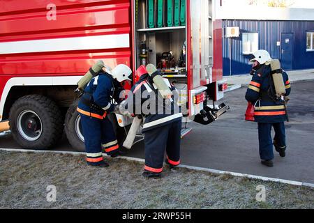 Group of firemen putting on gas masks and preparing for extinguish fire. Stock Photo