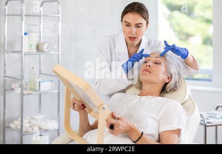 Elderly patient looking in mirror at clinic. Stock Photo