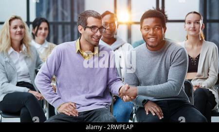 Happy multiethnic employees having fun while discussing project, sharing ideas, informal brainstorming sitting on chairs Stock Photo