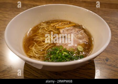 Japanese Shoyu soya sauce ramen noodles adorned with marinated bamboo shoots (menma), green onions, and sliced barbecued and braised pork (chashu). Stock Photo