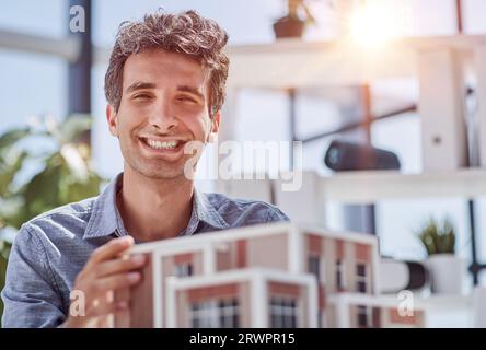 young caucasian engineer man making building model with the use of drawings and notes in office. Stock Photo