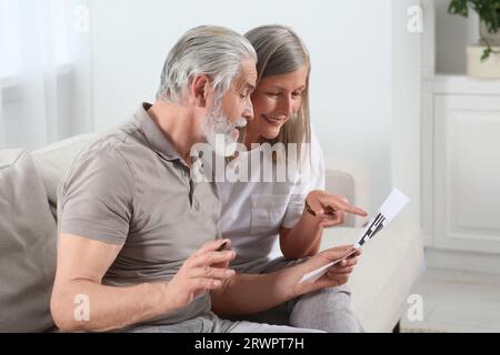 Senior couple solving crossword on sofa at home Stock Photo