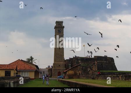Birds flying over the old clock tower at Galle Dutch Fort 17th Centurys. Ruined Dutch castle that is Unesco listed as a World Heritage Site in Sri Lan Stock Photo