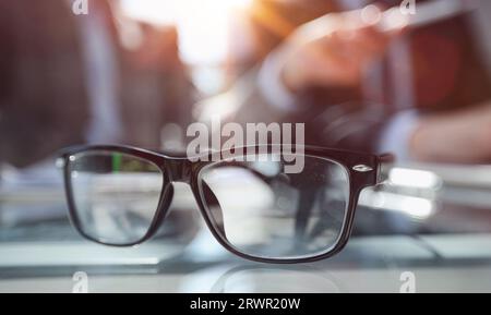 Close-up shot of business documents lying on meeting table, blurred silhouettes of male employees seen on background Stock Photo