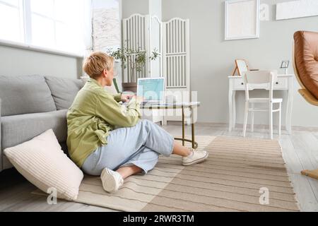 Mature female programmer working with tablet computer and laptop at home Stock Photo