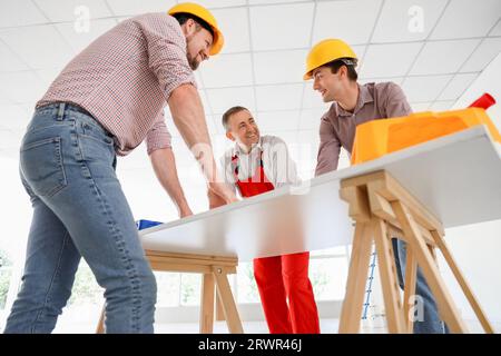 Team of male builders working at table in room Stock Photo