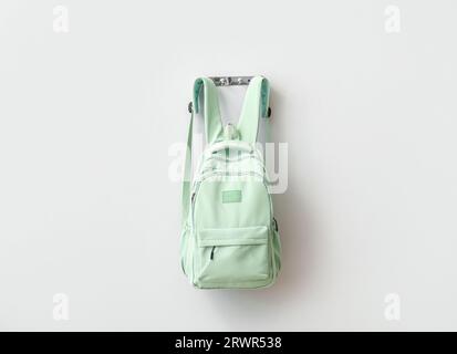 Stylish school backpack hanging on light wall Stock Photo