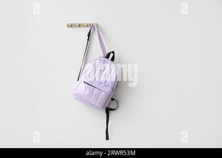 School backpack hanging on light wall Stock Photo