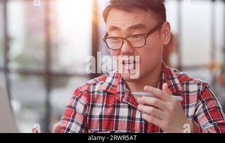 Portrait of a successful Asian software engineer working on a laptop at his desk. Stock Photo