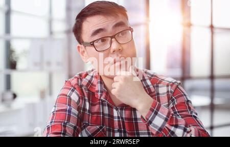 a young investor in casual clothes sits at a table and thinks about profit Stock Photo