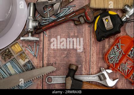 On a wooden board, a variety of tools needed for home repair are irregularly placed. Stock Photo