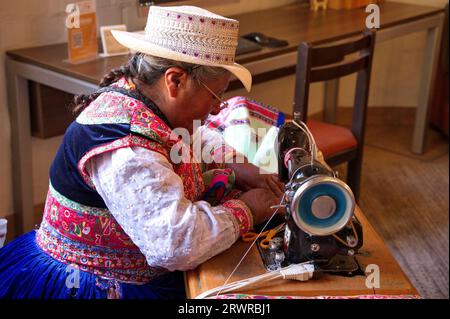Native woman in traditional clothes sewing on an old sewing machine Stock Photo