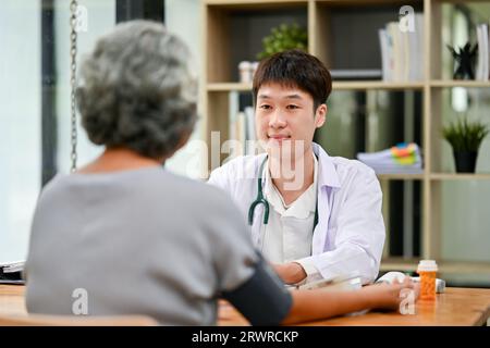 A professional Asian male doctor is diagnosing the disease and consulting treatment plans with an old lady patient in the hospital. Medical and health Stock Photo