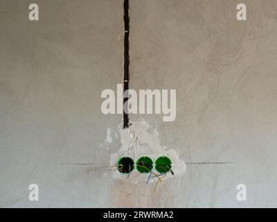 Plastic backbox for sockets or switches inserted into the drilled holes on wall Stock Photo