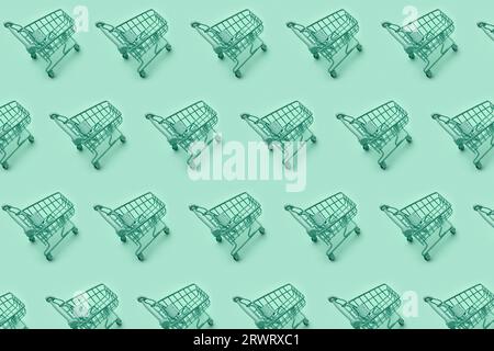 Mini shopping carts, mini shopping carts creative pattern background, top view, isolated on green. High quality photo Stock Photo
