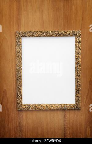 Old gilded photo frame with blank paper on wooden wall Stock Photo