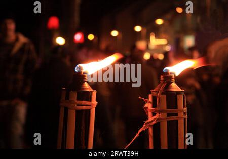 Two burning torches, background person in blur and colourful lights Stock Photo