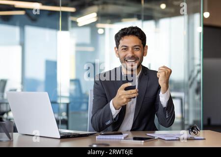 Portrait of successful arab businessman winner, man celebrating victory and successful triumph, smiling and looking at camera, boss received online email notification about good achievement results. Stock Photo