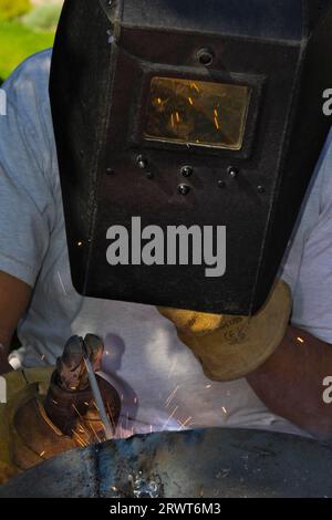 The welding of a piece of metal by means of an electric welder and a welding electrode. Man welded metals by means of an electric welder and a Stock Photo