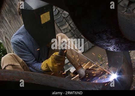 The welding of a piece of metal by means of an electric welder and a welding electrode. Man welded metals by means of an electric welder and a Stock Photo